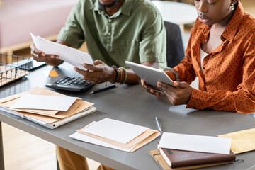 Poster - Close-up of African American couple sitting at table with bills and letters and analyzing month costs
