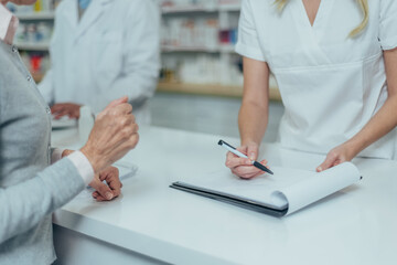 Wall Mural - Pharmacist giving prescription medications to smiling senior female customer