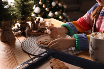 Wall Mural - Little child decorating Christmas cookie at wooden table, closeup