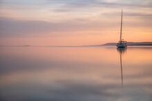 A Sailing Boat At Sunset On A Calm Lake