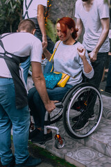 Wall Mural - Men help a woman in a wheelchair to descend the stairs not equipped with a ramp for the descent of people with  special needs