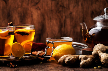 Canvas Print - Hot black winter tea with ginger, honey, lemon and spice. Immune booster drink in glass cup on rustic wooden table background, copy space