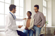 © Studio Romantic - Family visiting doctor for health check up. Professional gynecologist, OB GYN obstetrician, general practitioner or IVF pregnancy specialist talking to young black couple, reassuring and giving hope