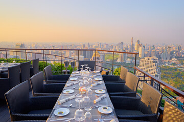 Wall Mural - Table setting on roof top restaurant with megapolis view, Bangkok Thailand.