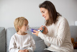 Fototapeta  - Mother, helping little toddler child with inhaler with spacer
