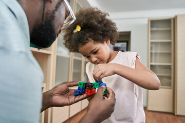 Joyful father and his daughter looking at building kit with satisfaction