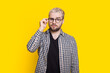 © Strelciuc - Portrait of a concentrated bearded man in eyeglasses looking at camera isolated over yellow background.