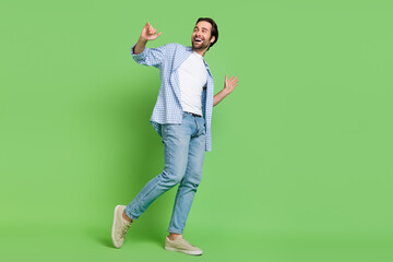 Canvas Print - Full size photo of joyful millennial guy move look empty space wear shirt jeans shoes isolated on green color background