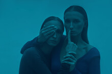 Woman Covering Eye Of Twin Sister In Blue Fog