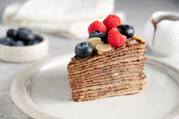 Wall Mural - Slice of chocolate crepe cake with berries on a plate