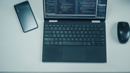 Poster - Top Down View of Laptop Computer with Developers Code on Screen, Smartphone with Rare Cameras and Computer Mouse on the Left. Professionals Software Engineers Create App on Laptop