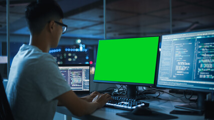Poster - Night Office: Young Japanese Man in Working on Green Screen Chroma Key Desktop Computer. Team of Programmers Typing Code, Creating Modern Software, e-Commerce App Design, e-Business Programming