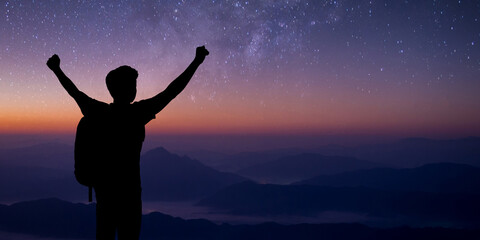 Wall Mural - Silhouette of young traveler standing and open both arm watched night sky view, star and milky way alone on top of the mountain. He enjoyed traveling and was successful when he reached the summit.