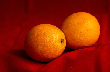 two oranges close up on red background