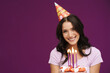 © Drobot Dean - White brunette woman in party cone posing with birthday cake
