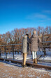 A man and a woman stand near the fence of the city embankment on a sunny winter day