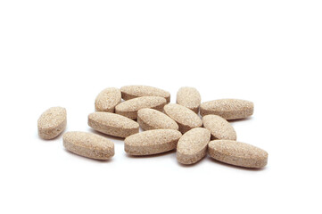 A handful of brown pills. Tablets or vitamins isolated on white background. Dietary supplements or Biologically Active Additives Tablets, BAA. Side view.