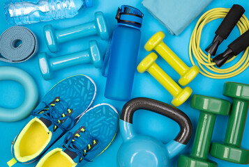 Wall Mural - Dumbbells, trainers, jumping rope and other fitness equipment on blue background, top view