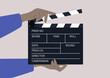 hands holding a clapperboard, a device used in filmmaking and video production to assist in synchronizing picture and sound