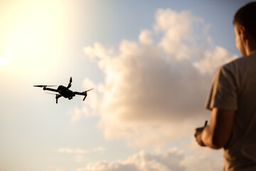 Wall Mural - man operating a drone, filming with sunset background.