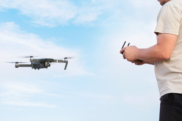 Wall Mural - man operating a drone, filming with a blue sky background.