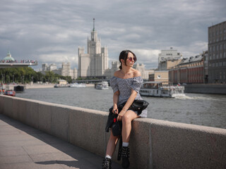 Beautiful woman walks on street at Moscow City sunny summer day.