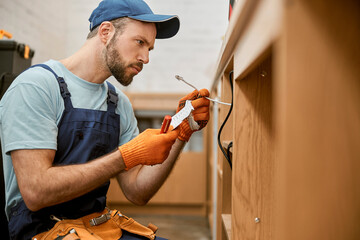 Wall Mural - Bearded male electrician fixing desk electrical wires