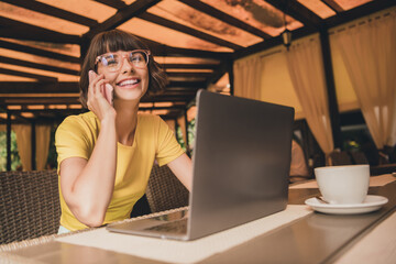 Poster - Photo of shiny positive lady dressed yellow t-shirt glasses sitting cafeteria drinking coffee talking modern gadget outdoors urban park