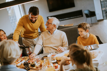 Wall Mural - Young man poring red wine to his father for testing during at home