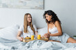 happy lesbian couple smiling near breakfast tray on bed