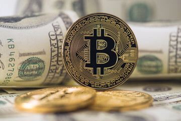 Closeup photo of gold coin with bitcoin symbol and dollar bills