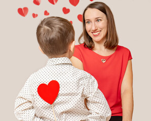 Child boy congratulates smiling mom and gives red heart on a stick. Concept for March 8, Mother's Day, Happy Valentines Day