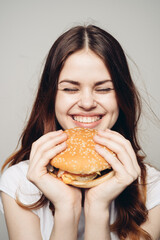 Wall Mural - woman with a hamburger in her hands a snack fast food close-up