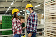 © Dusan Petkovic - The team at work in plaid shirts and with a protective yellow helmet and face mask talks about job in the warehouse. They have protected contact and behave responsibly at work. Coronavirus, covid19