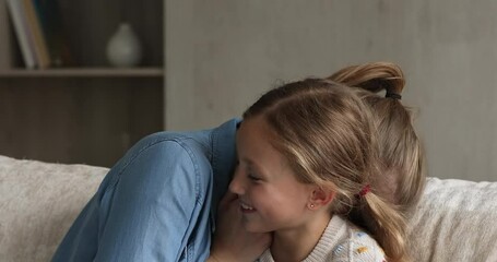 Wall Mural - Shh. Cute little child school age girl and teenage babysitter or grown elder sister making each other laugh whispering gossips to ear. Funny little daughter play with mom share secrets rumors on couch