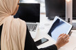 African american muslim girl with hijab working on a tablet in an office.