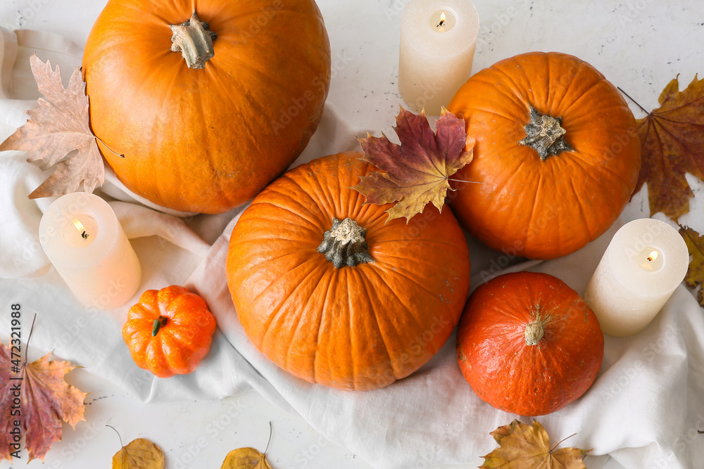 Fresh pumpkins and candles on light background
