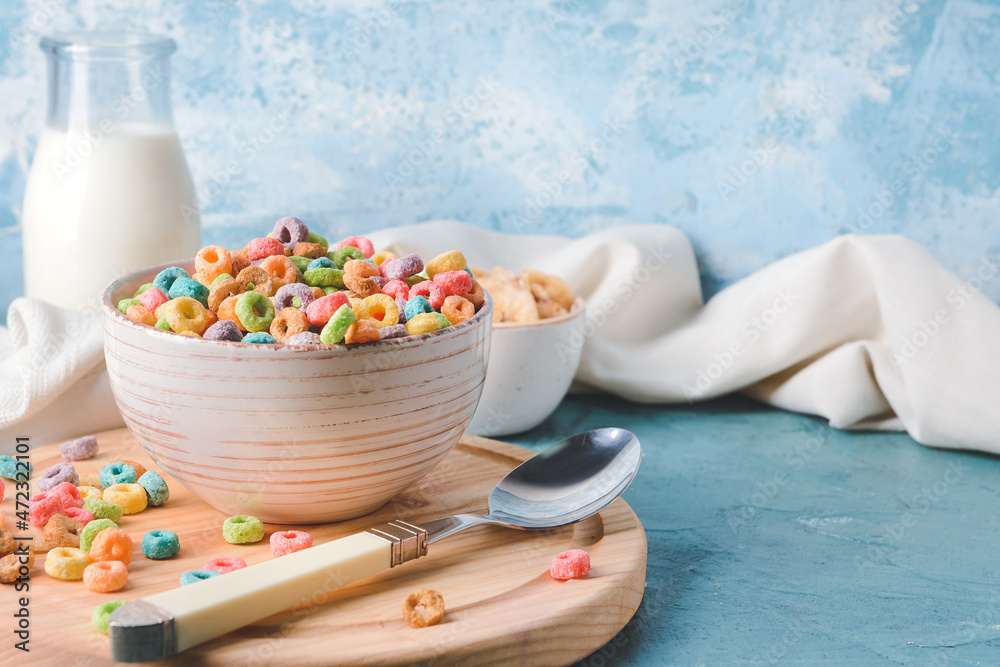 Bowl with crunchy corn flakes rings on color background