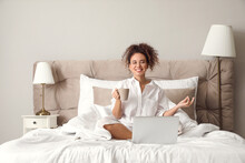 Morning of young woman with cup of tea and laptop in bed
