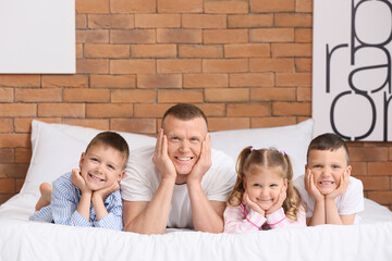 Wall Mural - Portrait of father with children in bed at home