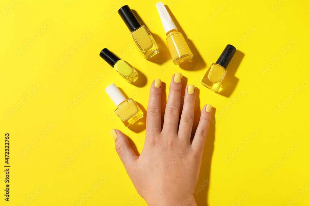 Female hand and nail polishes on yellow background