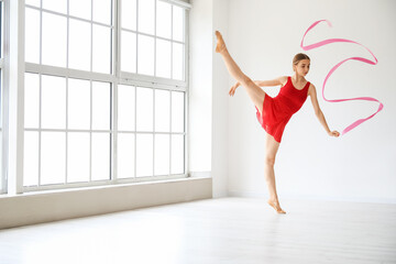 Wall Mural - Beautiful young woman doing gymnastics with ribbon in gym