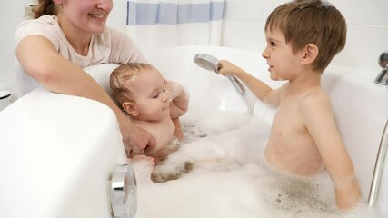 Wall Mural - Happy children having fun and playing with foam and shower in bathroom. Concept of children hygiene, healthcare and family care at home