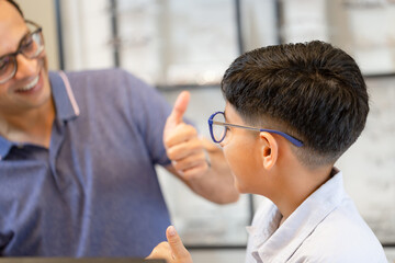 Wall Mural - Indian boy and father choosing eyeglasses in optics store, Happy Indian kid and dad in optics shop