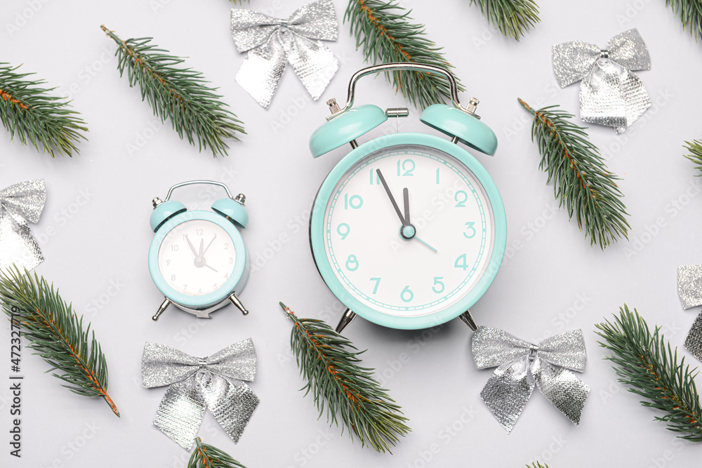 Christmas composition with alarm clock and fir branches on light background