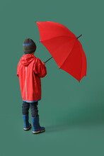 Little Boy In Raincoat And With Umbrella On Color Background