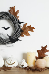 Wall Mural - Different pumpkin shaped holders, autumn leaves and burning candles on wooden table. Halloween decor