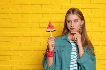 Poster - Beautiful girl with piece of watermelon near yellow brick wall. Space for text