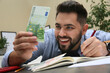 © New Africa - Young man with money at table indoors