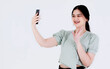 Studio shot of Asian young teen female model with ponytail hair wear dental care teeth braces and crop top outfit standing waving hand greeting say hi on smartphone video call on white background